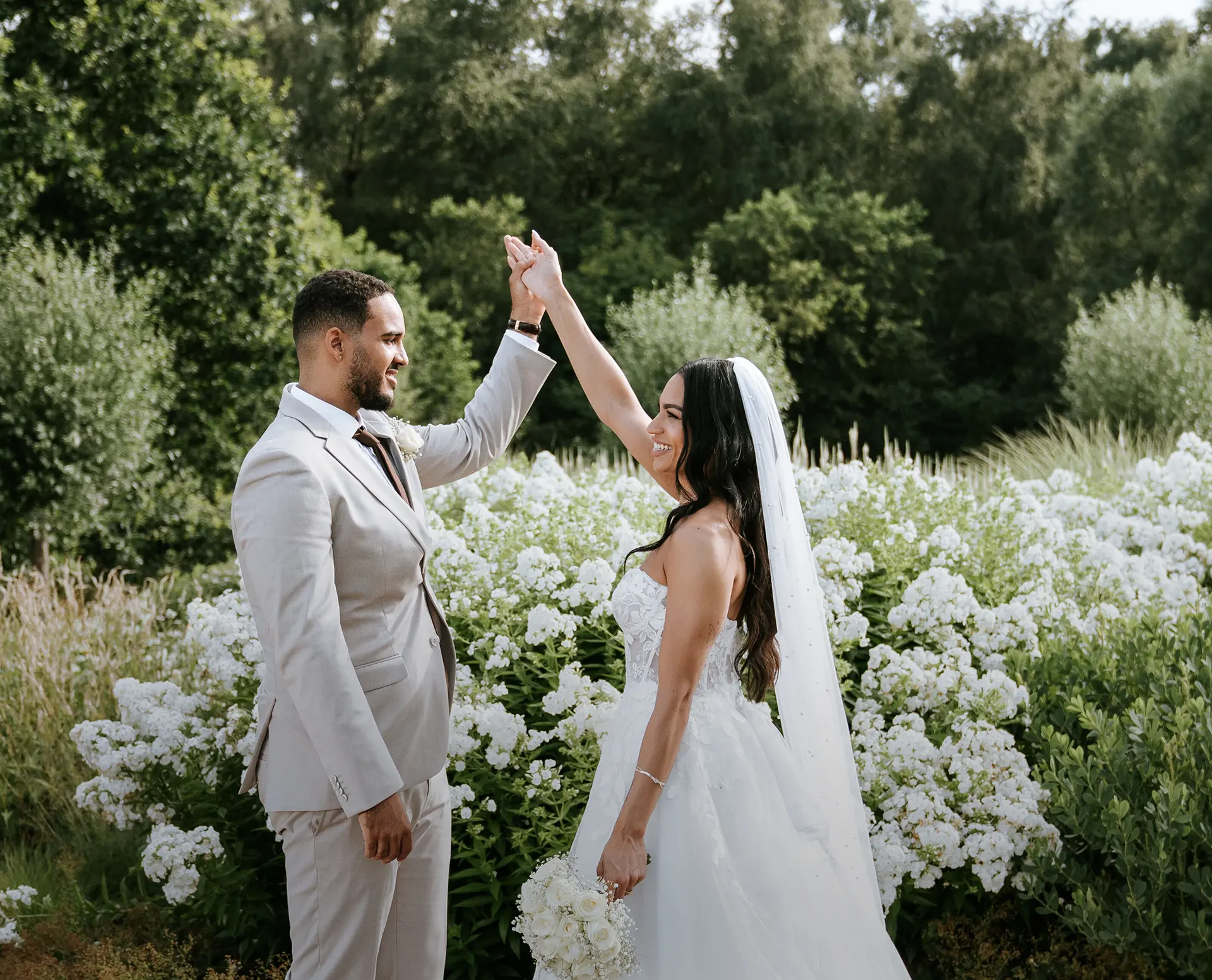 Braut und Bräutigam tanzen im blühenden Garten in Dortmund; Sommermoment mit Brautstrauß – natürliche Hochzeitsfotografie, hochzeitsbilder draußen