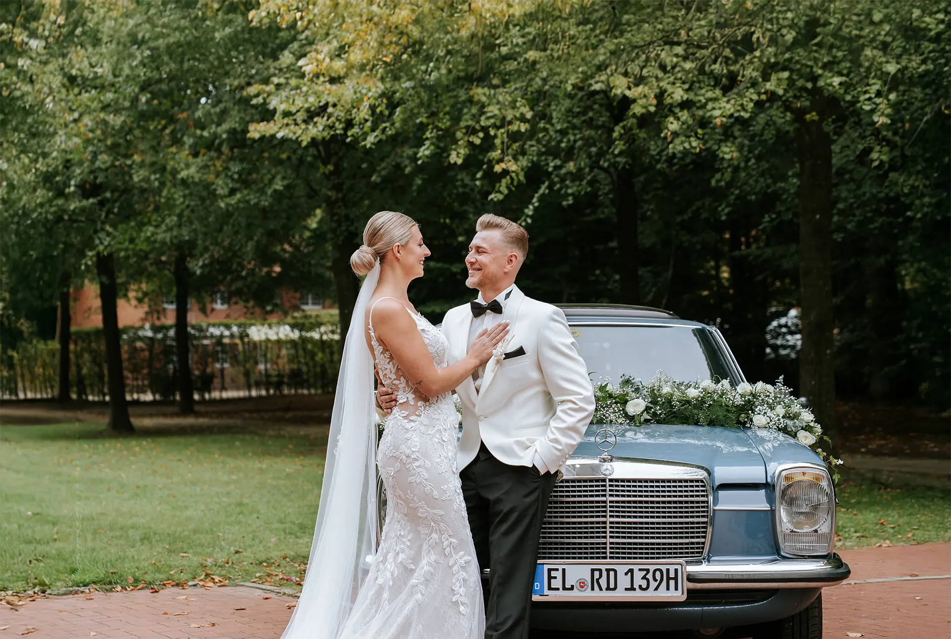 Brautpaar Hand in Hand im Garten, von dichtem Heckenbogen eingerahmt; eleganter Blick zurück in zeitloser Schwarzweiß, natürliche hochzeitsfotografie und hochzeitsbilder draußen