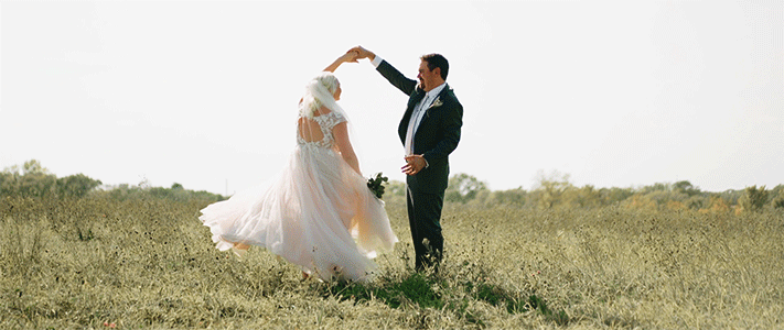 bride and groom dancing and kissing in an open field