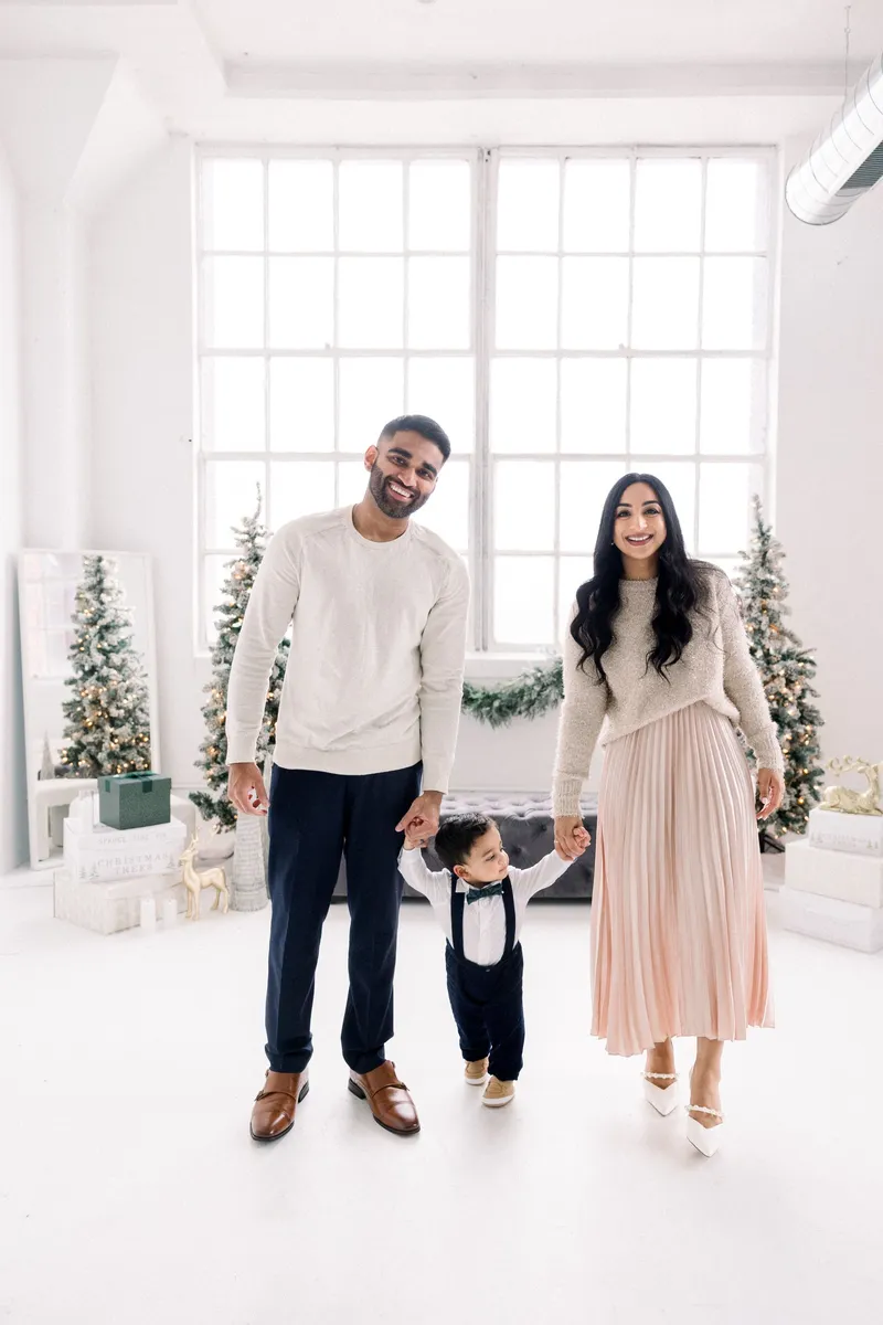 Family of three holding hands in the holiday studio