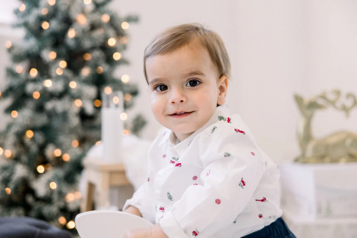 Toddler smiling in front of a lit tree